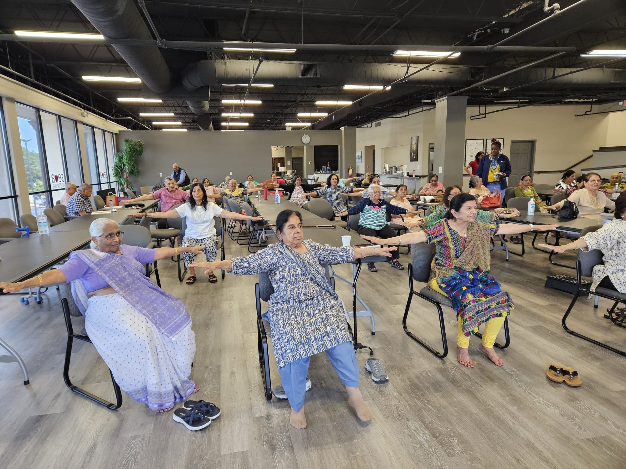 Seniors doing chair yoga together during a live group session